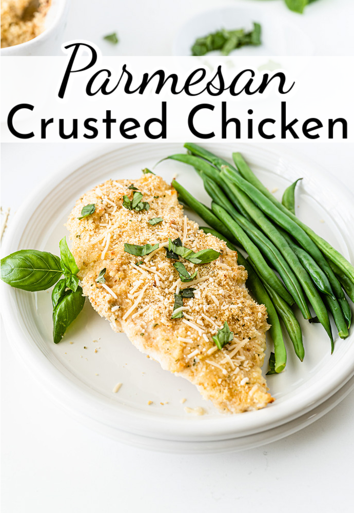 cooked chicken breast on a white plate with side of green beans; text label reads: Parmesan Crusted Chicken