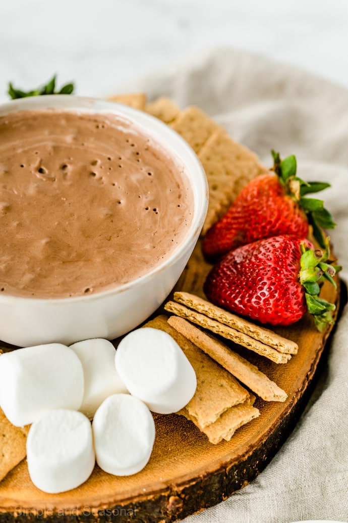 closeup of wooden platter holding s'mores dip and dipping food