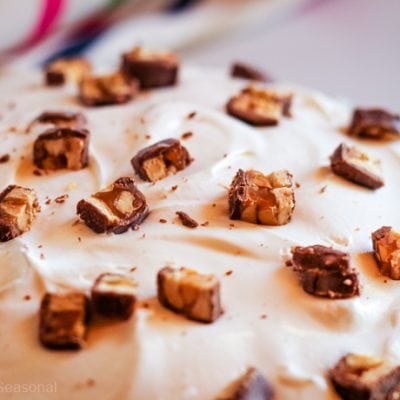 closeup of whole snickers pie showing creamy filling and topped with chunks of Snickers bars
