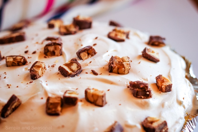 closeup of whole snickers pie showing creamy filling and topped with chunks of Snickers bars