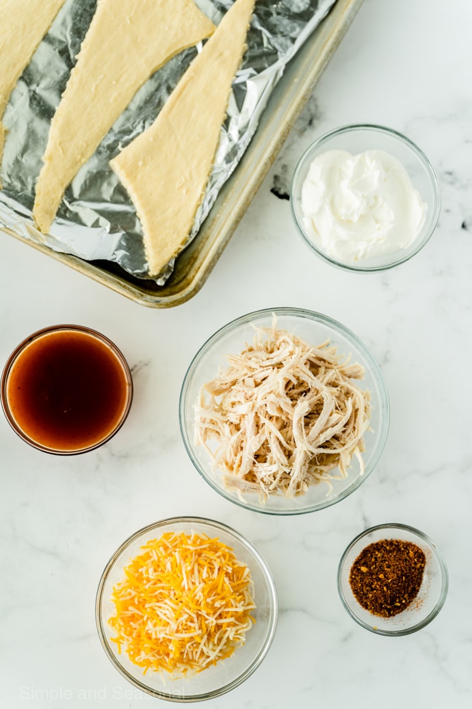 ingredients for chicken enchilada puffs: crescent roll dough, cooked chicken, cheese, taco sauce and seasoning and cream cheese