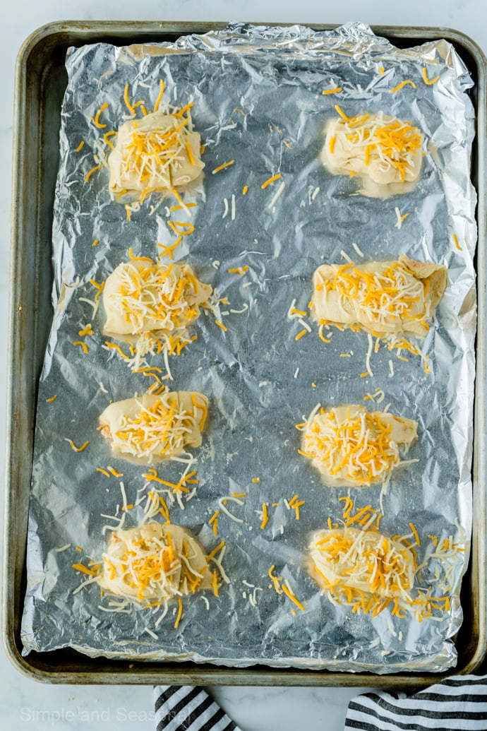 8 chicken enchilada puffs on a baking sheet, sprinkled with cheese