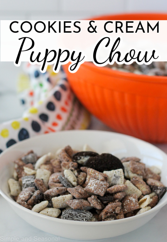 snack mix in a white bowl with a large orange bowl in the background; text label reads: Cookies and Cream Puppy Chow