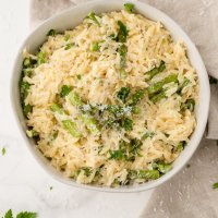 cooked orzo and asparagus in a bowl sprinkled with Parmesan cheese
