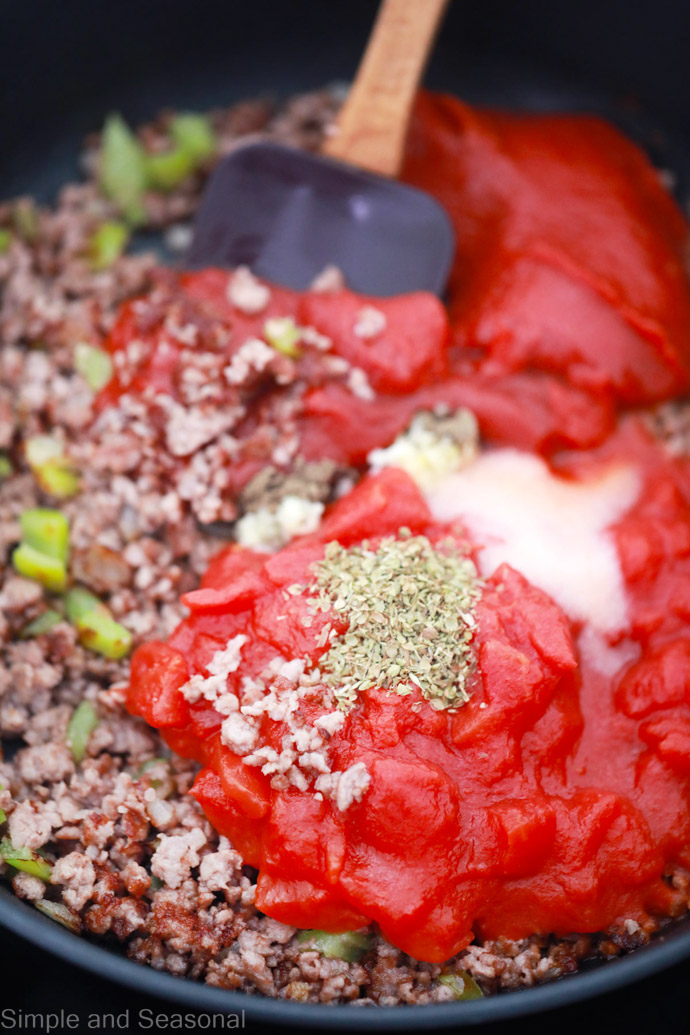 skillet with browned ground beef, tomato paste and seasonings