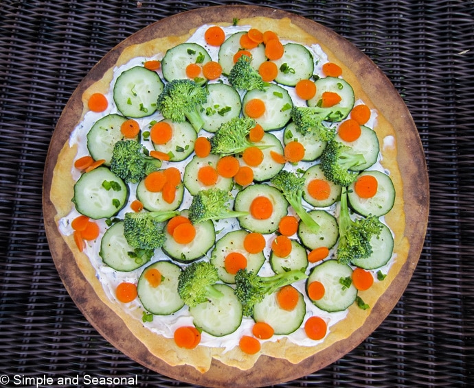 top down view of pizza topped with cream cheese and fresh vegetables