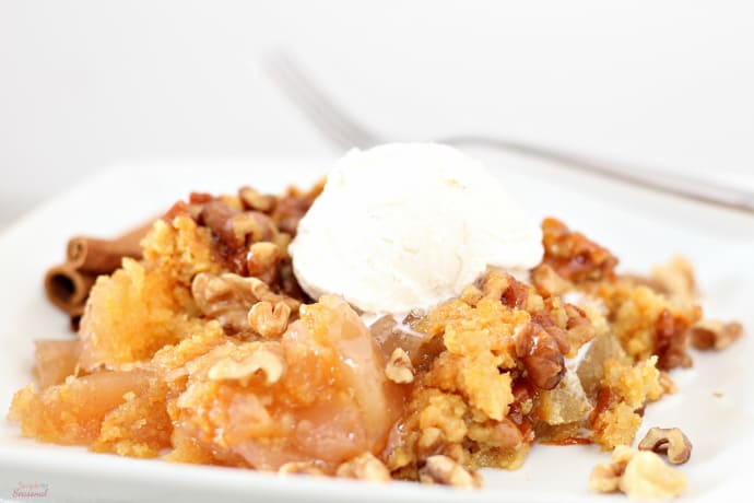 cooked apple cinnamon dump cake topped with ice cream on a white plate