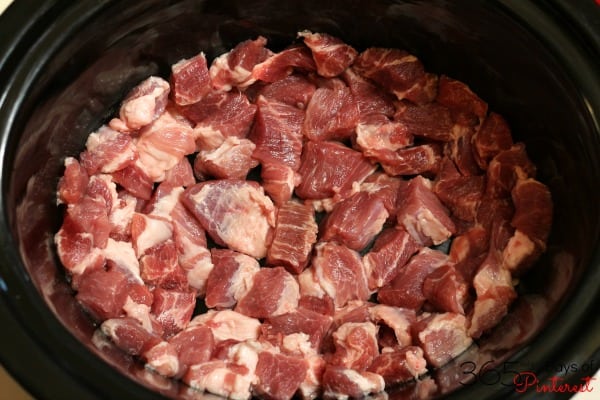 raw pork shoulder pieces inside a slow cooker crock