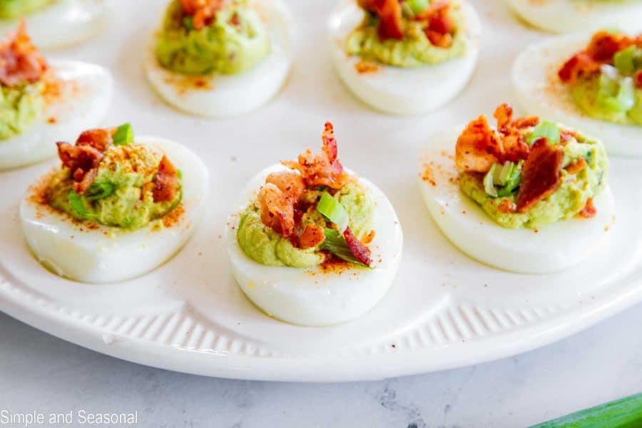 close up of bacon avocado deviled eggs on a white tray