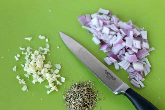 chopped garlic, red onion and oregano on cutting board