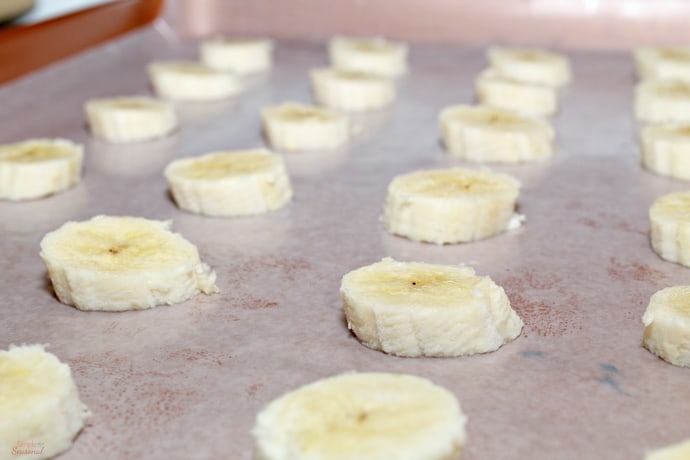 banana slices on a sheet pan lined with parchment paper