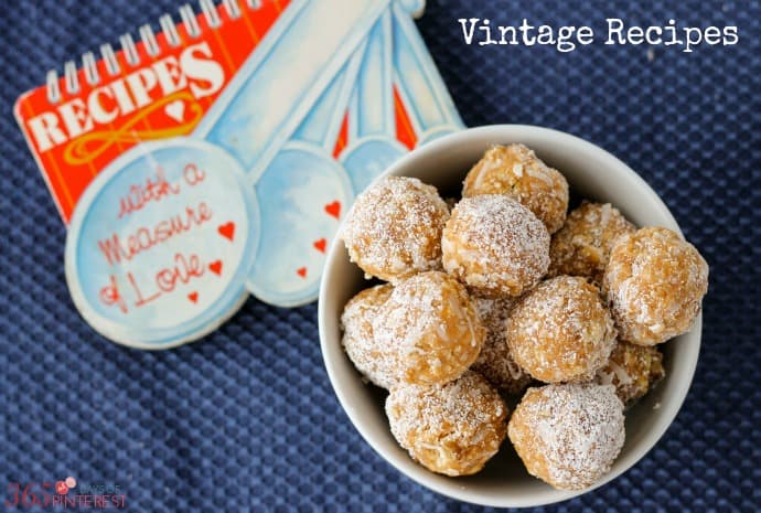 orange cookie balls in a white bowl with a vintage recipe book