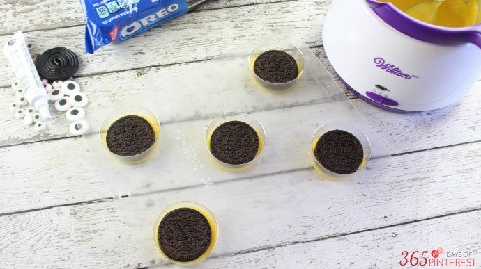 oreo cookie sitting on top of melted yellow candy in cookie mold