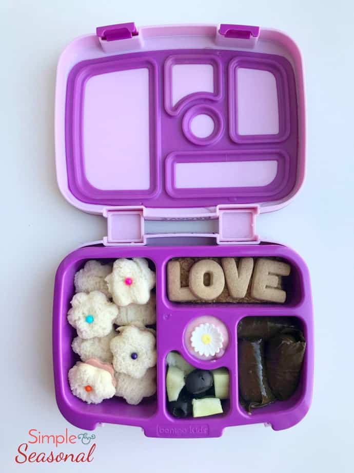 flower shaped mini sandwiches, grape leaf rolls and alphabet crackers in bento box
