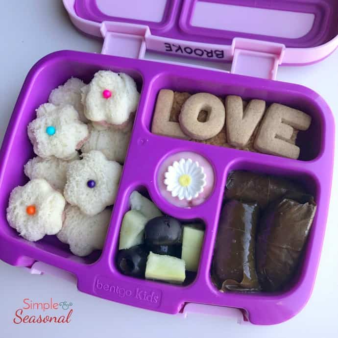 flower shaped mini sandwiches, grape leaf rolls and alphabet crackers in bento box