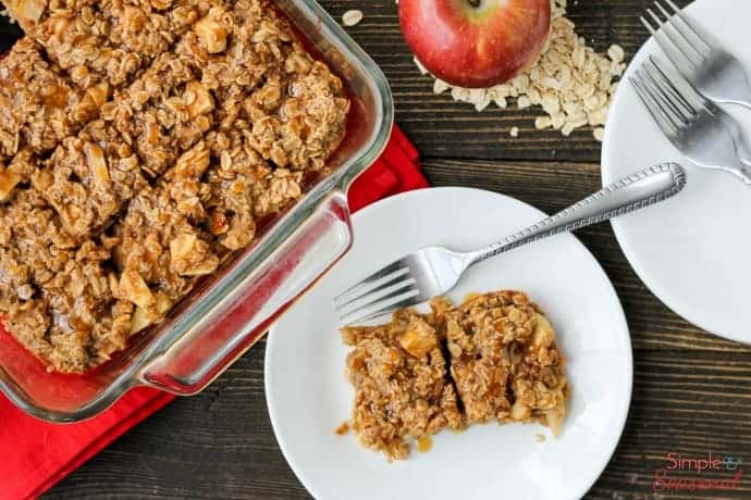 plates and forks next to a pan of baked oatmeal with apples and oats on the side