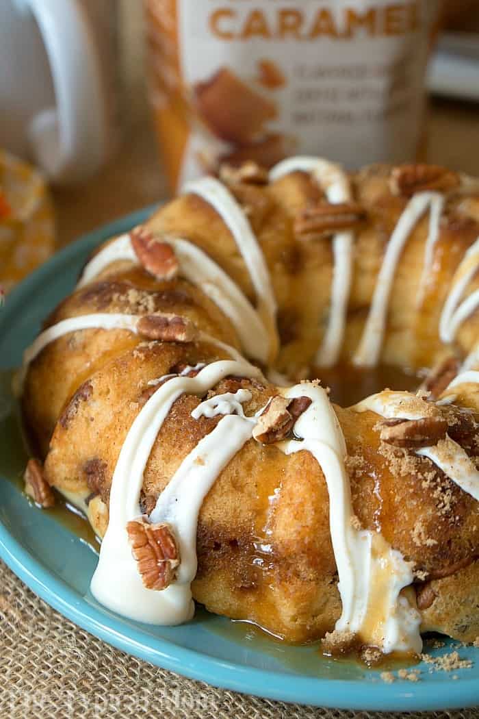 coffee cake on blue plate, topped with frosting and pecans