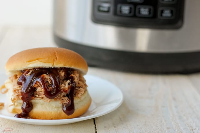 horizontal image of pulled pork sandwich with pressure cooker in the background