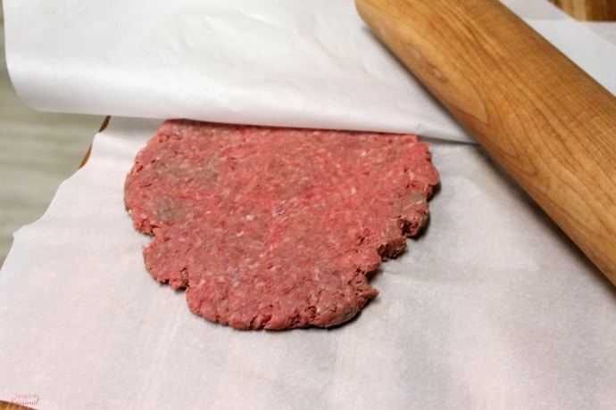 flat burger between layers of parchment