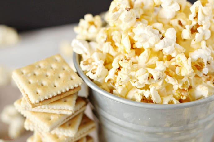 silver bucket with popcorn in it  and stack of crackers next to it