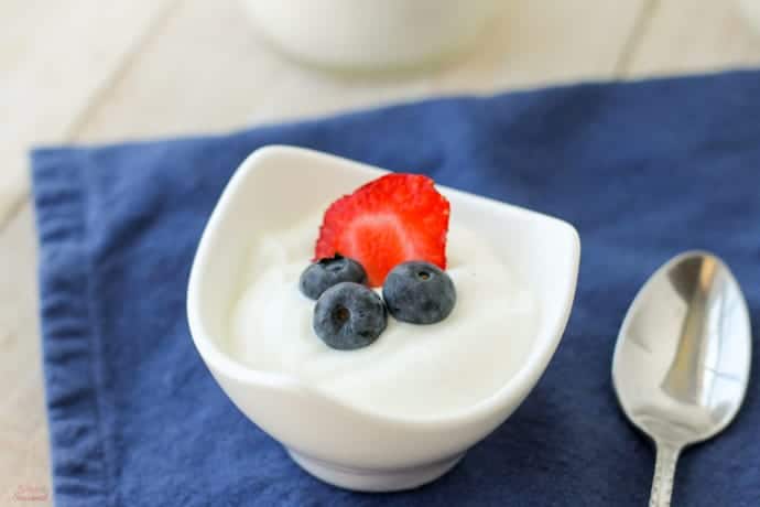 closeup of bowl of plain yogurt topped with berries
