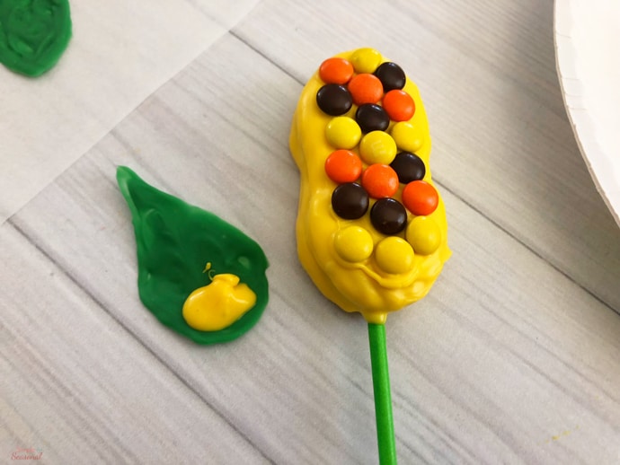 attaching candy leaf to corn pop with more melting candy
