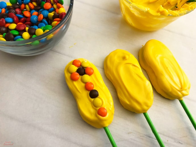 decorating melted candy topping with yellow, orange and brown mini M&M's