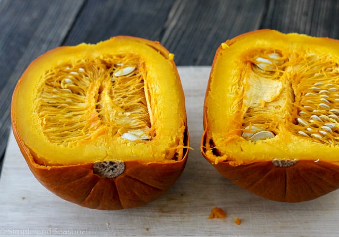 cooked pumpkin cut in half showing insides and seeds