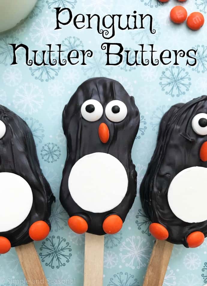 nutter butter cookies decorated to look like penguins with melting chocolate and candies