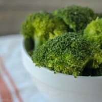bright green cooked broccoli stems in a white bowl