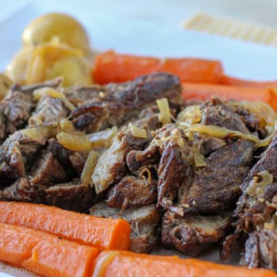horizontal image showing cooked pot roast topped with cooked onion