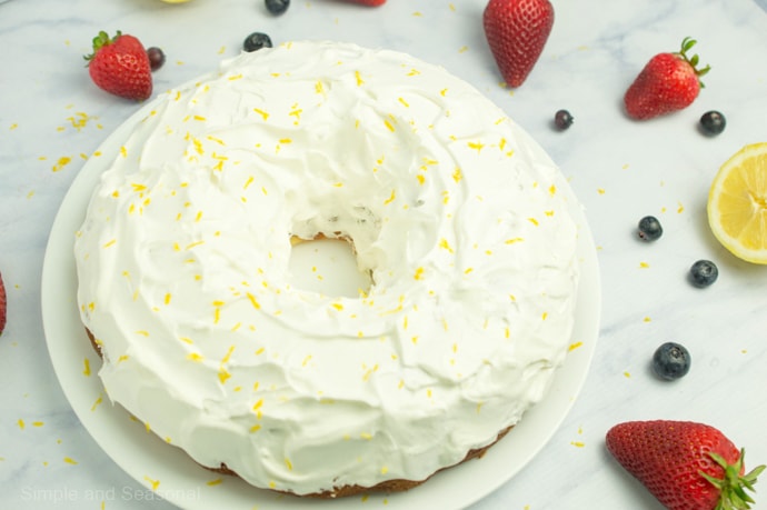 Lemon Bundt Cake put back together and covered with whipped topping and fresh lemon zest