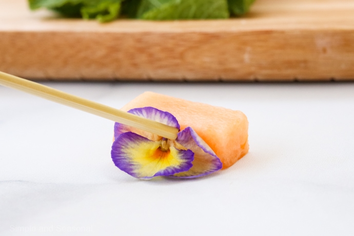 pressing edible flowers into melon to look like wings