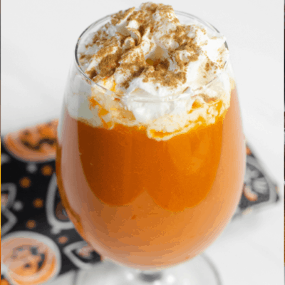 glass with orange pumpkin punch topped with whipped cream labeled: Pumpkin Pie Punch