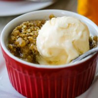 closeup of apple crisp in a bowl with ice cream melting on top