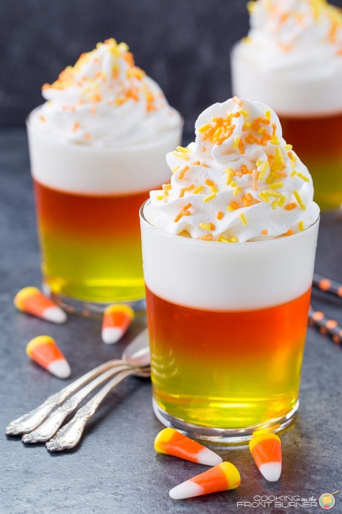 layered jello in shot glasses topped with whipped cream and sprinkles