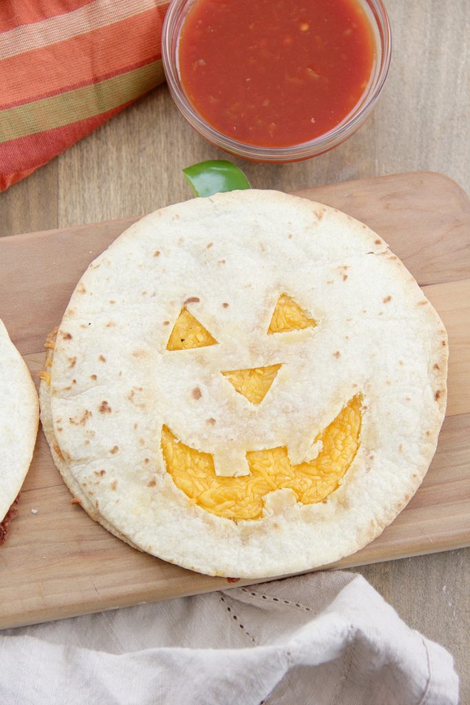 tortilla cut with jack-o-lantern face, filled with cheese to be a quesadilla