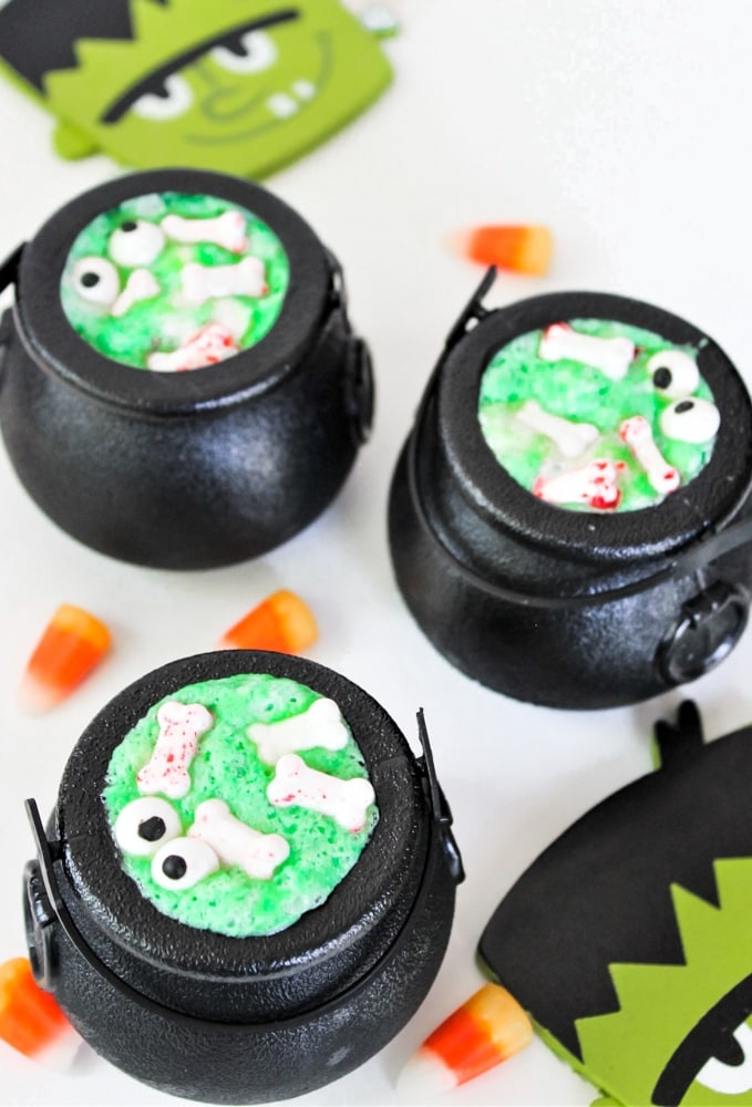 small pots filled with green bubbly pudding mixture and topped with candy bones