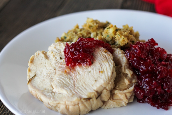 plate of Thanksgiving food: turkey breast slice, cranberry sauce and stuffing