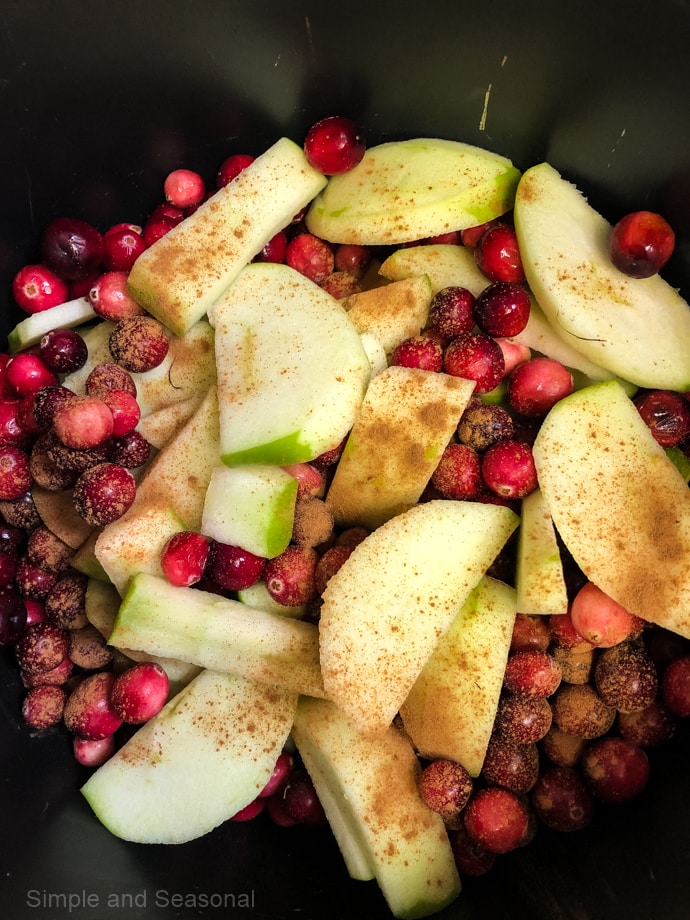 pot filled with apple slices, cranberries and cinnamon