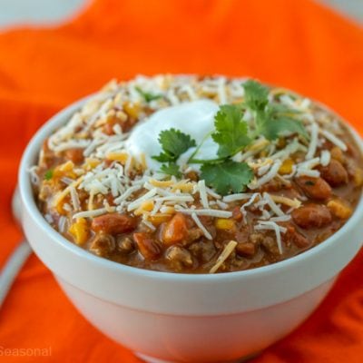 closeup of bowl of taco soup topped with cheese, sour cream and cilantro