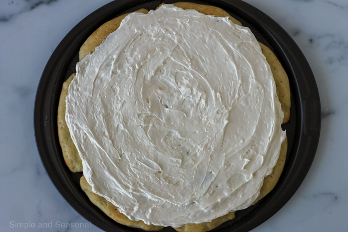 pizza crust covered with cream cheese spread