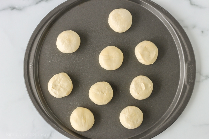 pizza pan with 9 rolls of dough on it