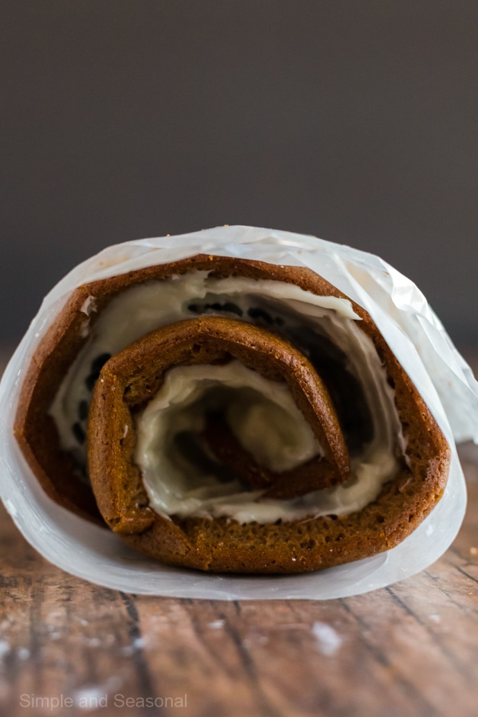 side view of pumpkin roll after filling with frosting and rolling up again