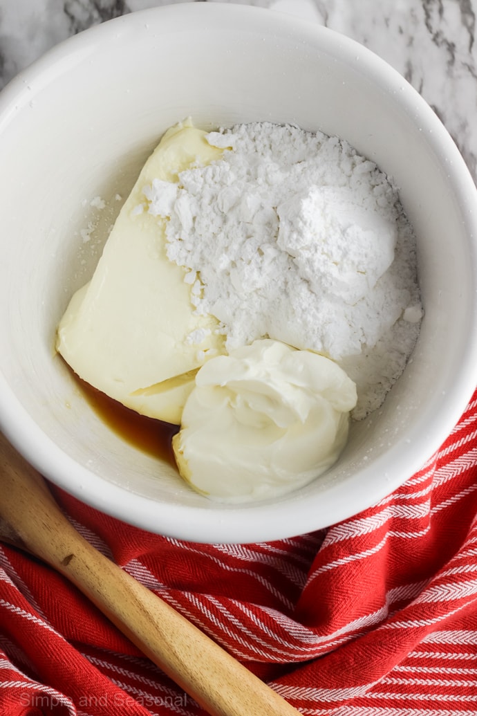 white bowl with cream cheese, sour cream, powdered sugar and vanilla inside