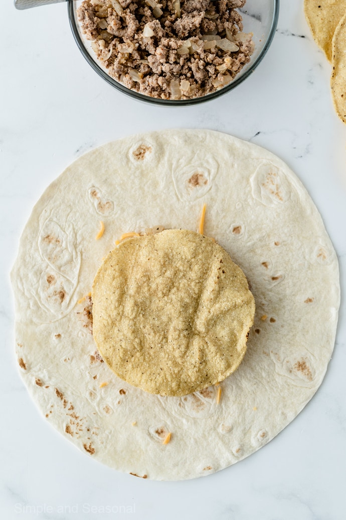 taco meat and cheese covered by small tostada shell