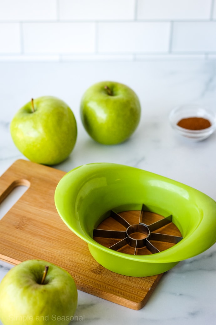 apple cutting tool on a wooden cutting board with green apples