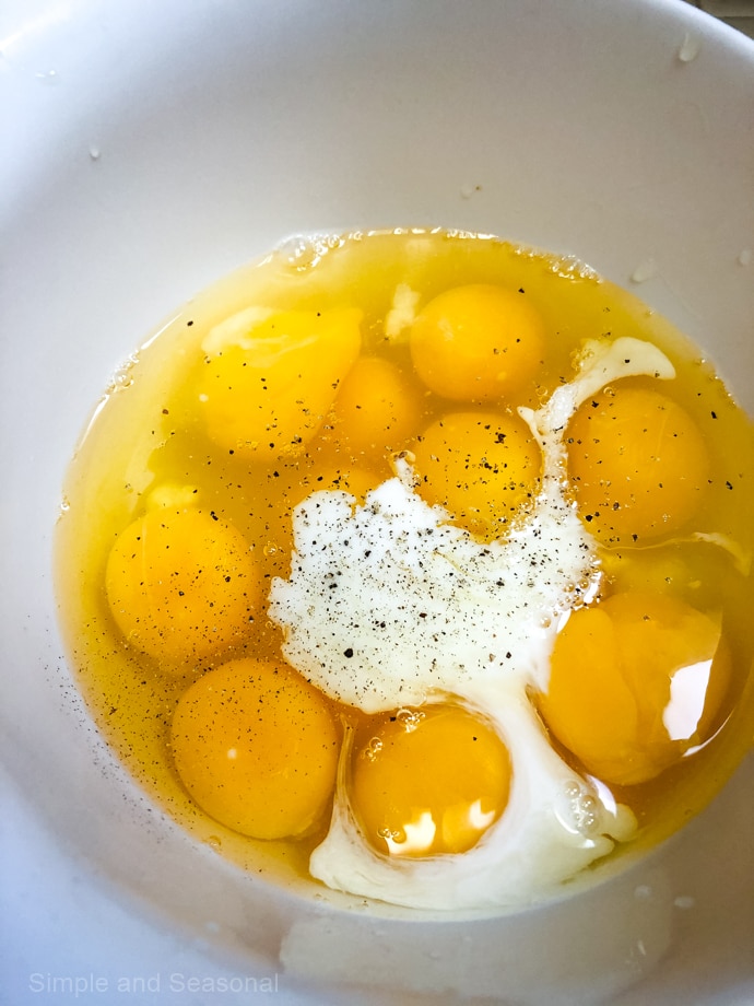 12 eggs in a bowl with a splash of milk