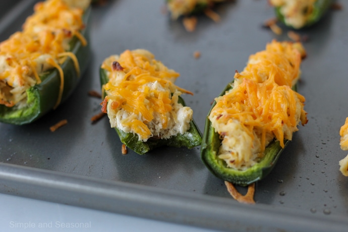 crack chicken jalapeno poppers on a baking sheet-one with a bite taken out of it