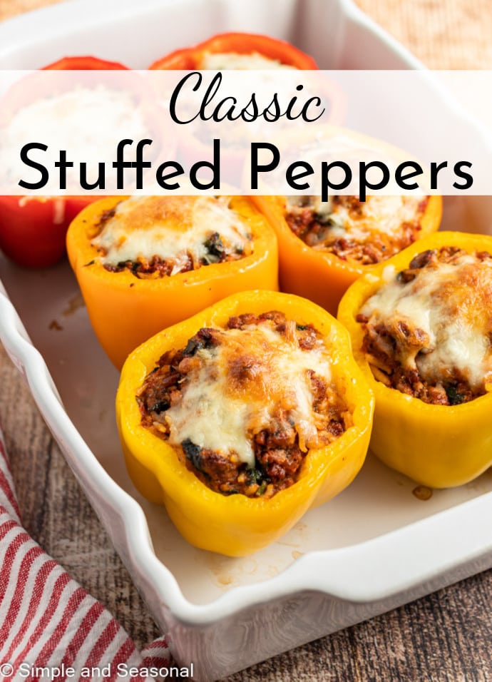 yellow and red stuffed peppers in a white baking pan